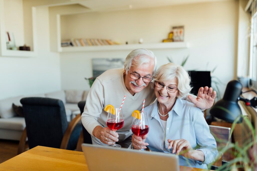 elderly couple with cocktails watching a laptop