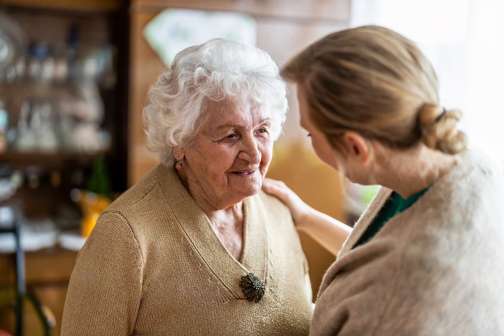 Senior woman is embraced by younger female