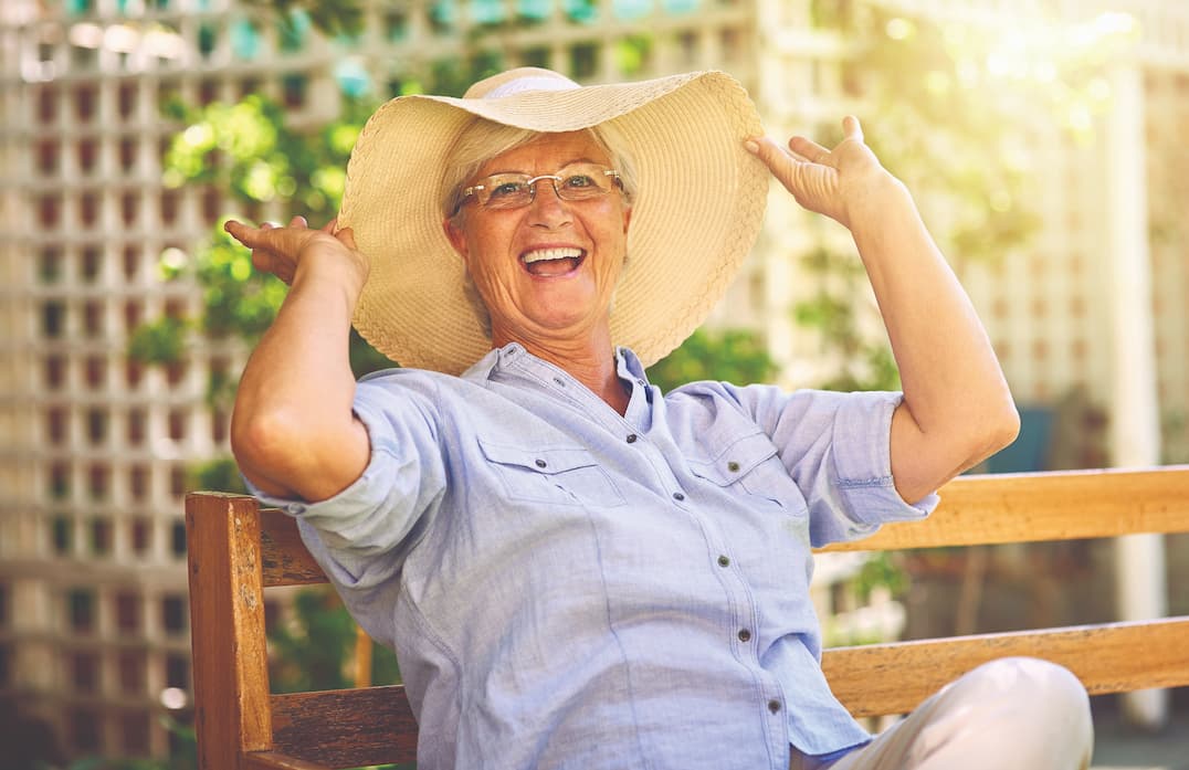 Senior woman smiling and holding up her large sunhat