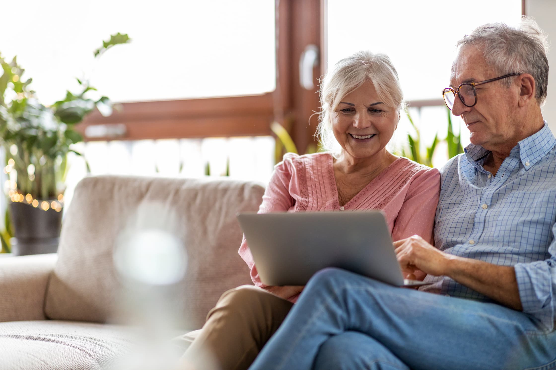 Happy senior couple using laptop in their home