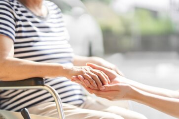 Close up of senior woman holding hands with caregiver