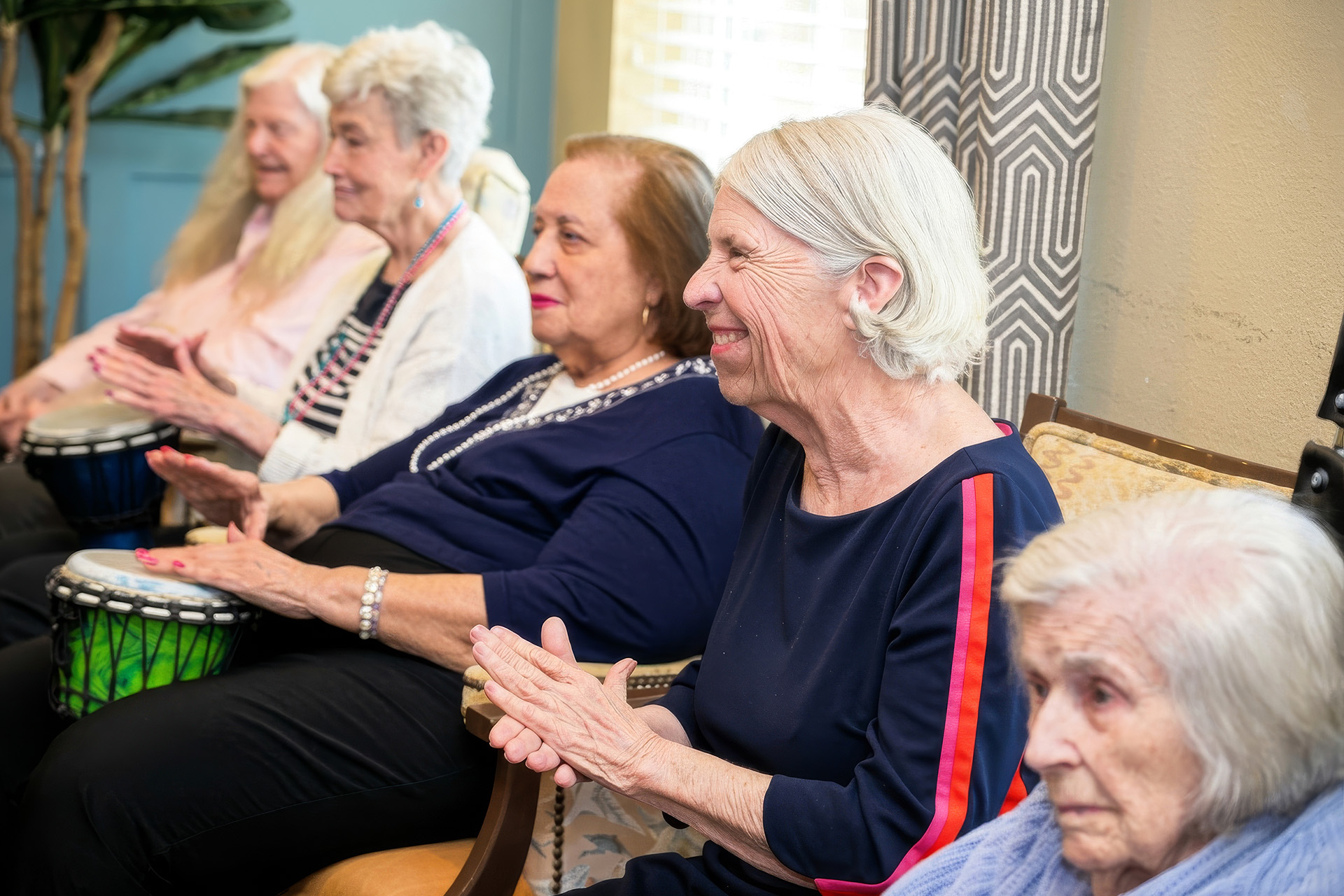 Elderly women enjoying a drumming session in a communal area.