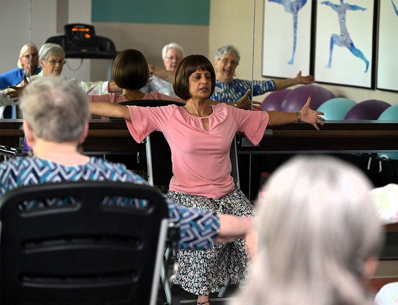 Exercise with seniors and instructor in a mirrored studio.