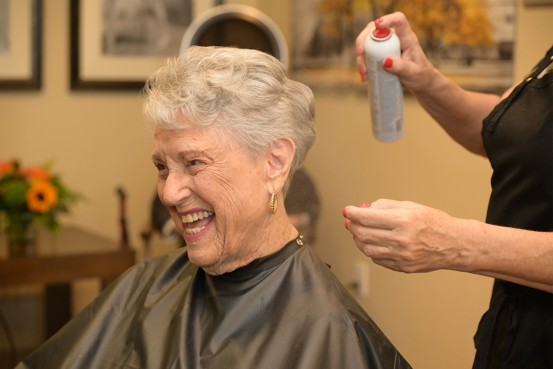 Elderly woman enjoying a haircut and styling in senior living salon.