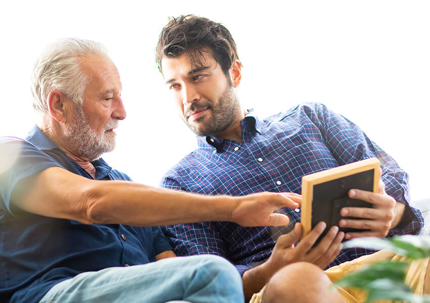 Young man and senior man talking about a framed image